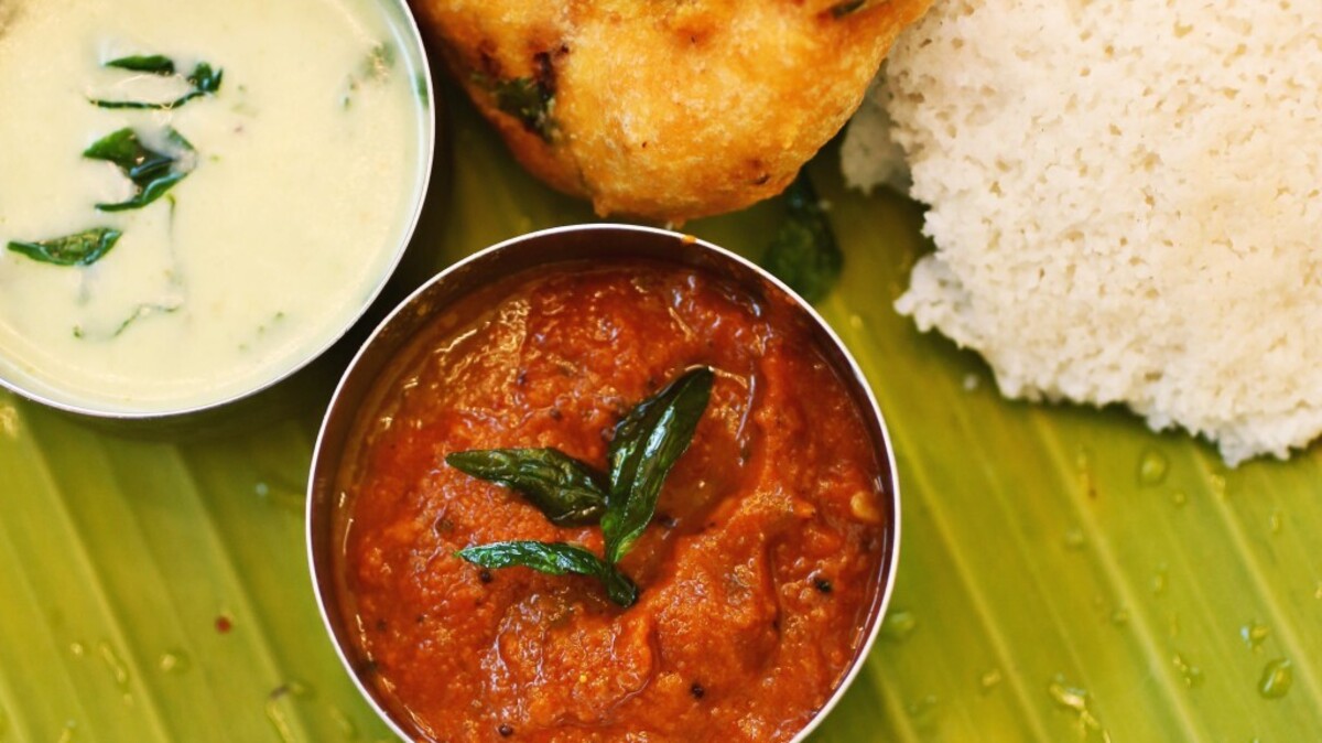 Idly vada, a popular Southern Indian pairing of pale, pillowy rice cakes and a donut-shaped, cilantro- and chile-flecked fritters are served on a banana leaf with the traditional accompaniments of sambar, coconut chutney and tomato chutney at Persis Indian Grill in Cary.