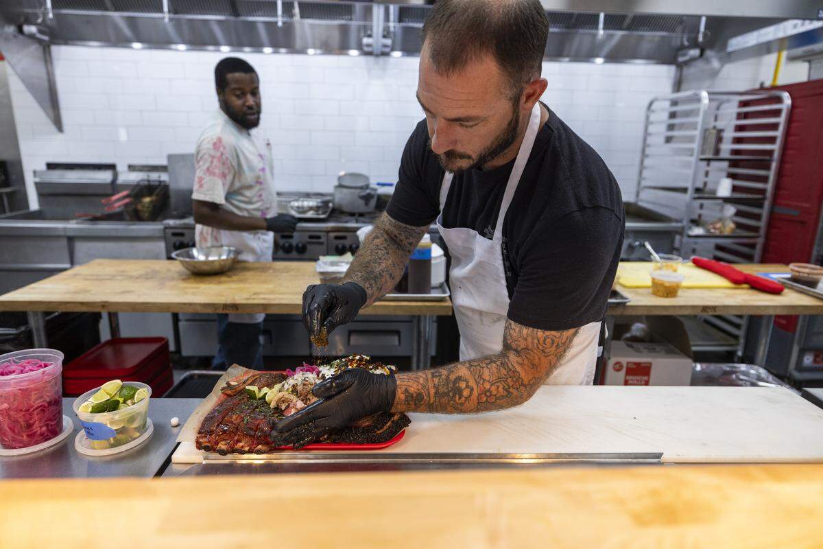 Lawrence Barbecue owner Jake Wood prepares a barbecue tray ahead of the grand opening of the restaurant’s new downtown Cary location on Cedar Street.