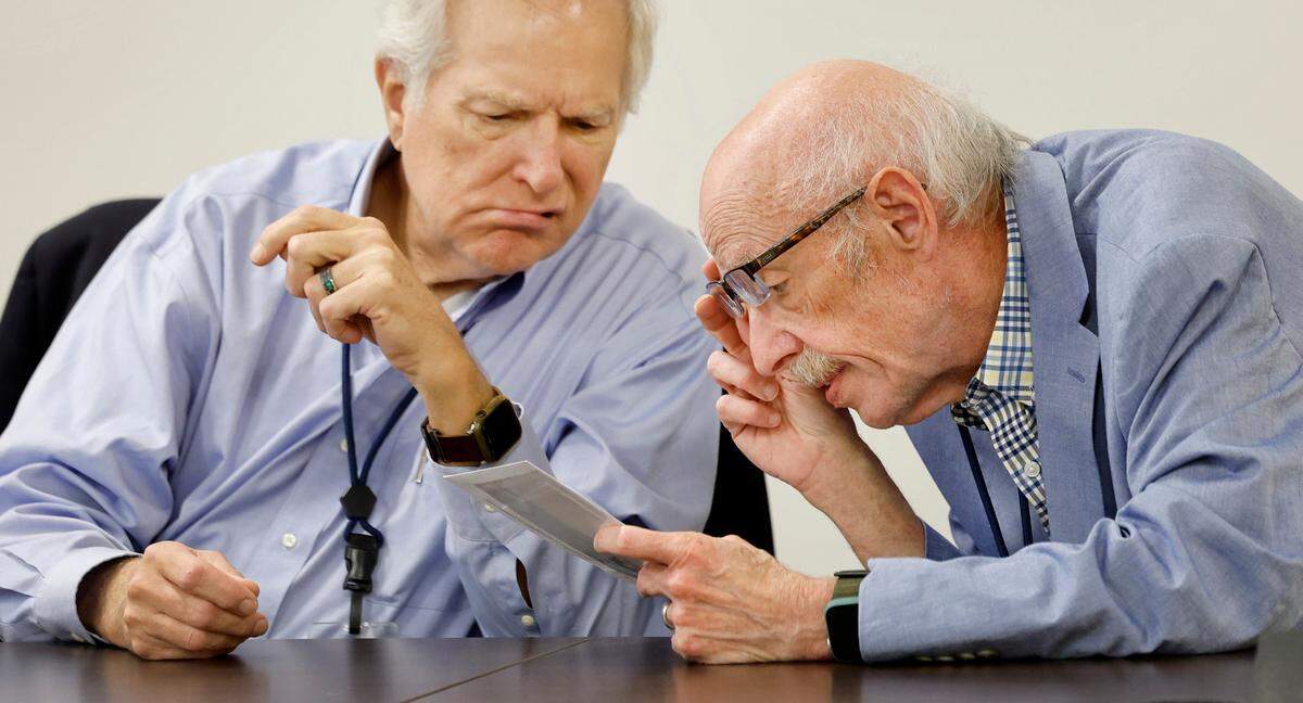 Wake County Board of Elections members Keith Weatherly, left, and Gerry Cohen inspect an absentee ballot during a board meeting at the Wake County Board of Elections Operations Center in Raleigh, N.C., Tuesday, Oct. 8, 2024.
