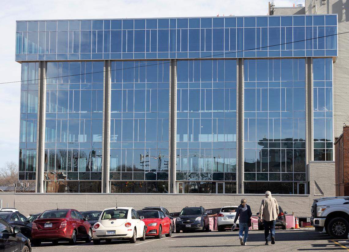 People walk in a parking lot next to a building at 136 Rosemary Street, a site that will become a part of Chapel Hill’s new downtown innovation district, on Friday, Jan. 20, 2023.