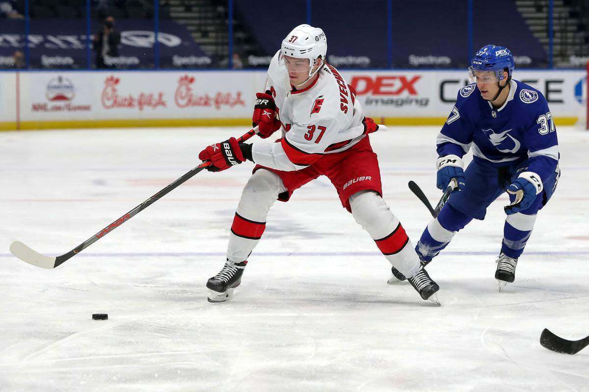Carolina Hurricanes’ Andrei Svechnikov, left, of Russia, avoids the check of Tampa Bay Lightning’s Yanni Gourde during the first period of an NHL hockey game Monday, April 19, 2021, in Tampa, Fla. (AP Photo/Mike Carlson)