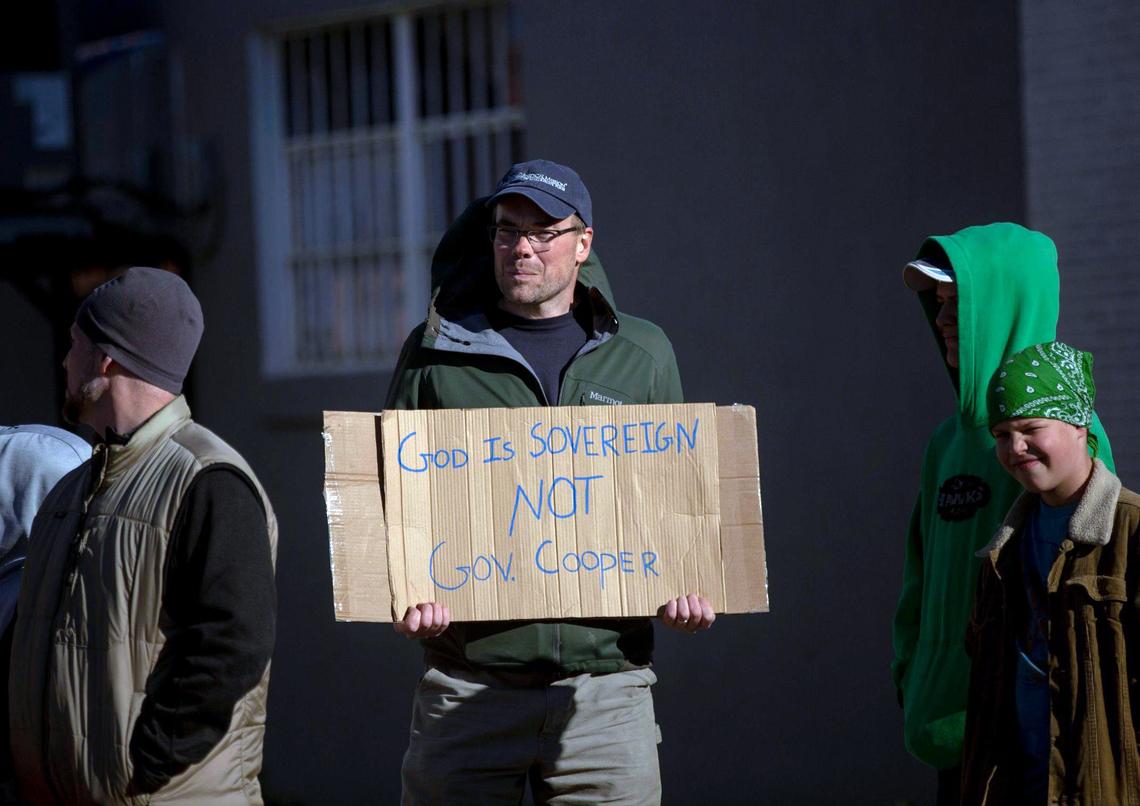 Nathan Garner holds a sign while gathered with his family and friends along East Main St., for the Christmas parade in Youngville, N.C., held despite warnings from the Franklin County Health Department about spiking COVID-19 cases, and in defiance of Gov. Roy CooperÕs executive order, on Saturday, Dec 5., 2020.