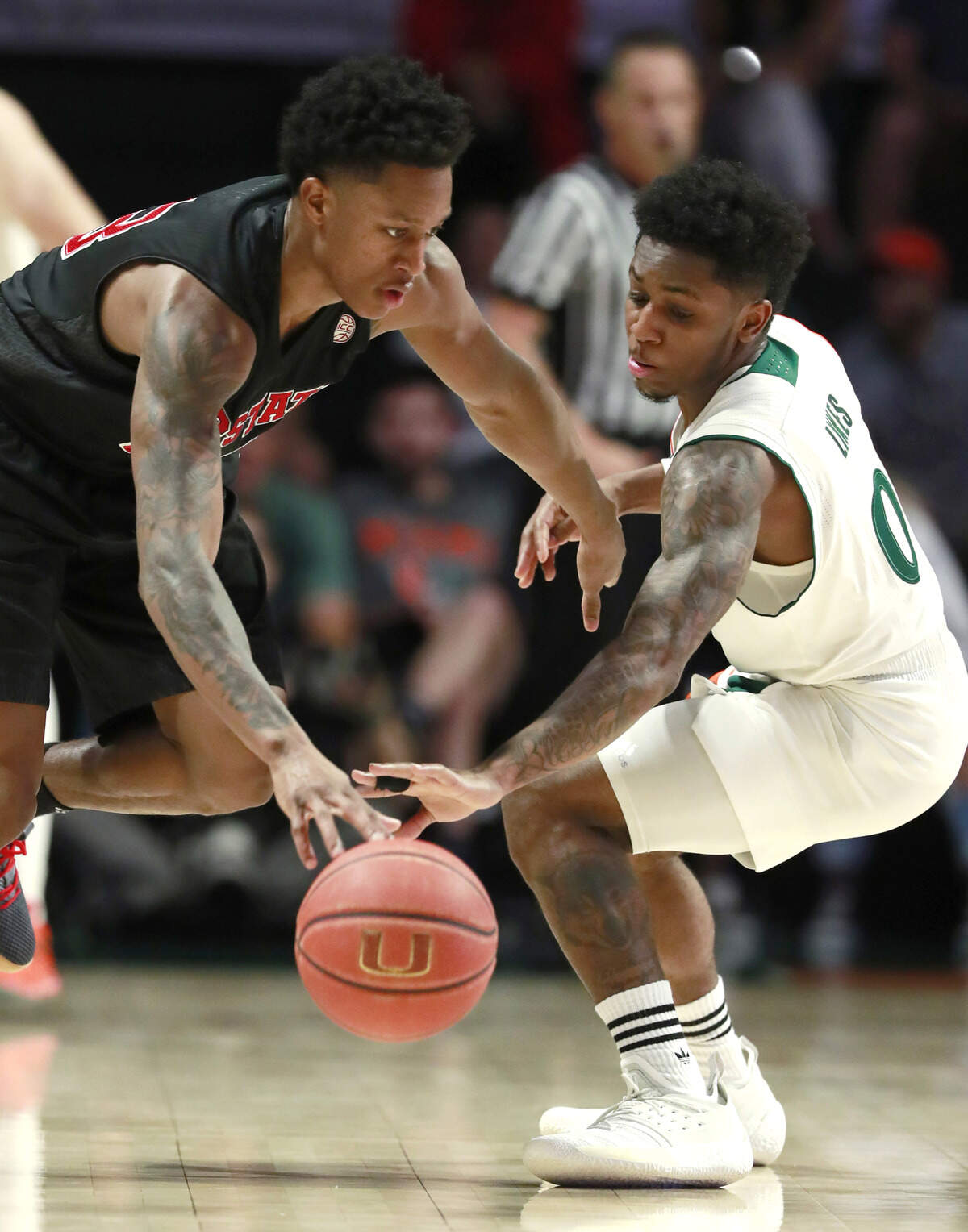 N.C. State guard C.J. Bryce, left, attempts to drive past Miami guard Chris Lykes (0) during the first half of an NCAA college basketball game, Thursday, Jan. 3, 2019, in Coral Gables, Fla.