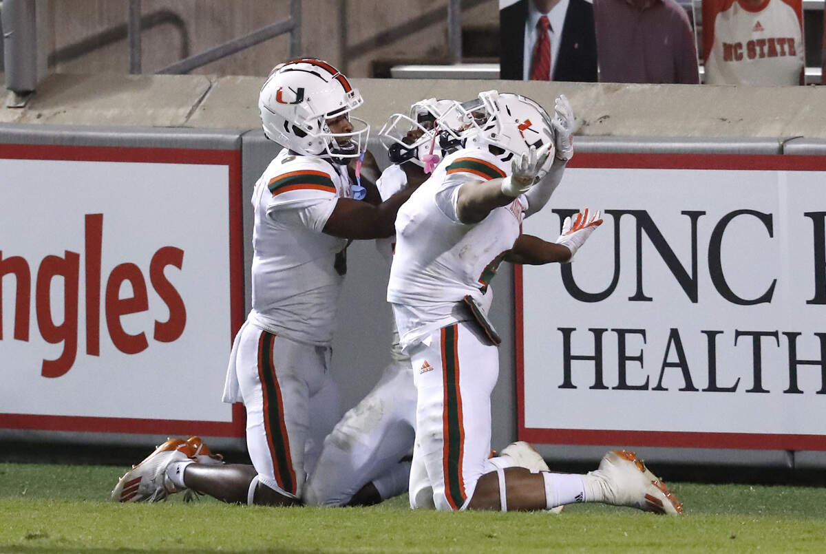 Miami’s Mark Pope (6), left and Jaylan Knighton (4), right, celebrate with Mike Harley (3) after Harley scored on 54-yard touchdown during the second half of Miami’s 44-41 victory over N.C. State at Carter-Finley Stadium in Raleigh, N.C., Friday, Nov. 6, 2020.
