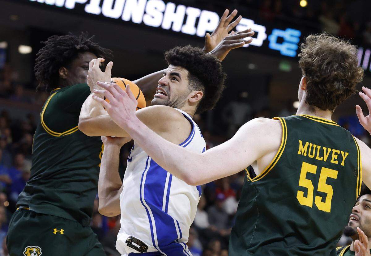Duke’s Cayden Boozer (2) drives through the defense of Siena’s Francis Folefac (11) and Riley Mulvey (55) in the second half of Duke’s 71-65 victory over Siena in the first round of the NCAA Men’s Basketball Tournament at  Bon Secours Wellness Arena in Greenville, S.C., Thursday, March 19, 2026.