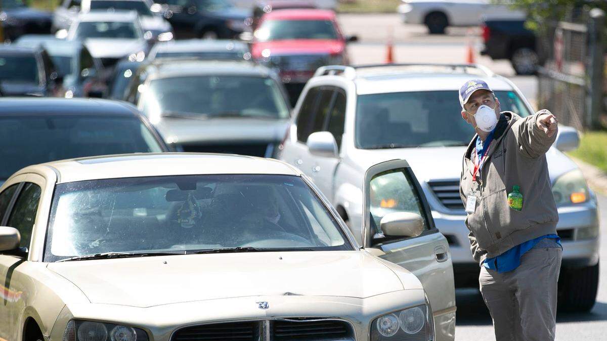 John Hammond directs traffic at the entrance to the North Carolina State Farmers Market on Thursday morning, sending the majority of people into a long line to purchase chicken by the case from the House of Raeford, and the others to the produce area on Thursday morning April 16, 2020 in Raleigh, N.C.