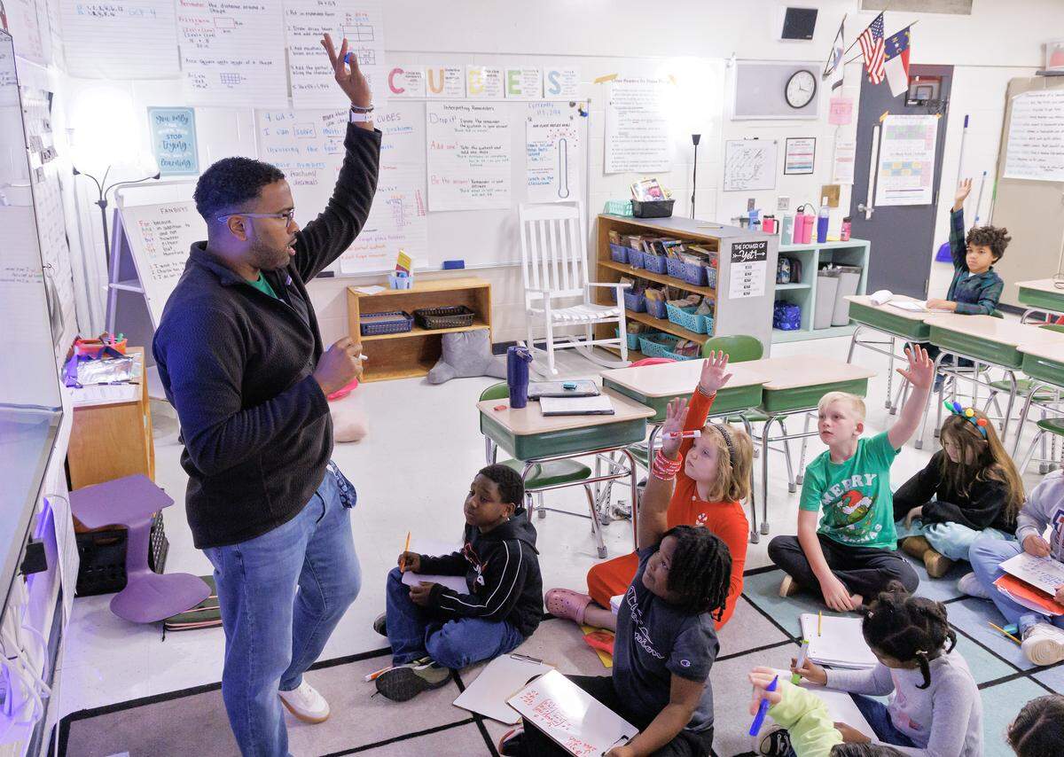 Fourth-grade teacher Shane Henderson, who began his career as a school-bus driver, works with students in class at Pittsboro Elementary School. 