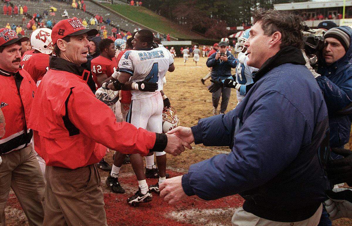 UNC coach Mack Brown, right, and N.C. State head coach Mike O’Cain shake hands after the Tar Heels’ 30-28 victory in 1995.
