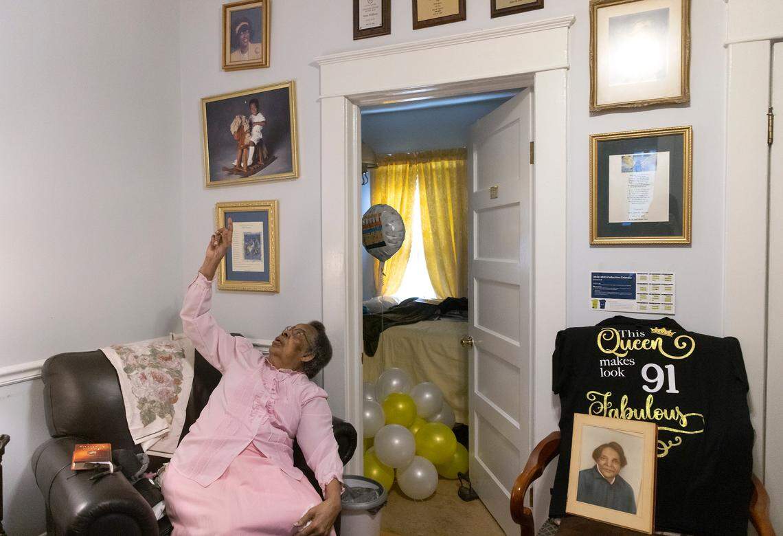 Doris Williams, 91, points to photographs on the wall of her home in Raleigh, N.C. on Thursday, Jan. 26, 2023. Williams has lived in the house since she was five years old. At right is a portrait of her great-Aunt Annie Brooks Vaughn, the first child to live in the house.