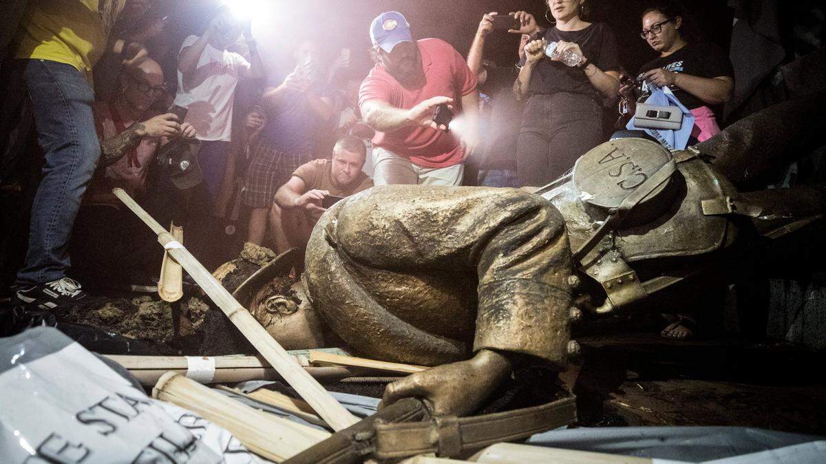 Demonstrators and spectators gather around a toppled Confederate statue known as Silent Sam Monday, August 20, 2018 at UNC-Chapel Hill. Demonstrators surrounded and obscured the statue with large banners before toppling it.