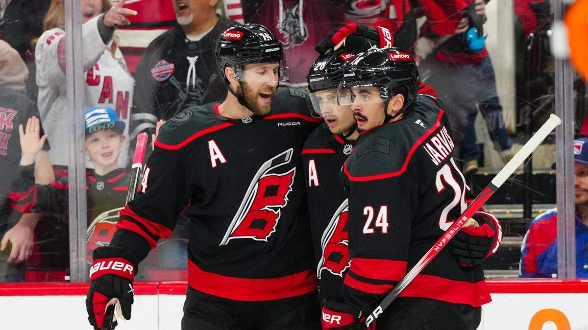 Apr 12, 2025; Raleigh, North Carolina, USA; Carolina Hurricanes center Seth Jarvis (24) is congratulated by center Sebastian Aho (20) and defenseman Jaccob Slavin (74) after his goal against the New York Rangers during the first period at Lenovo Center. Mandatory Credit: James Guillory-Imagn Images
