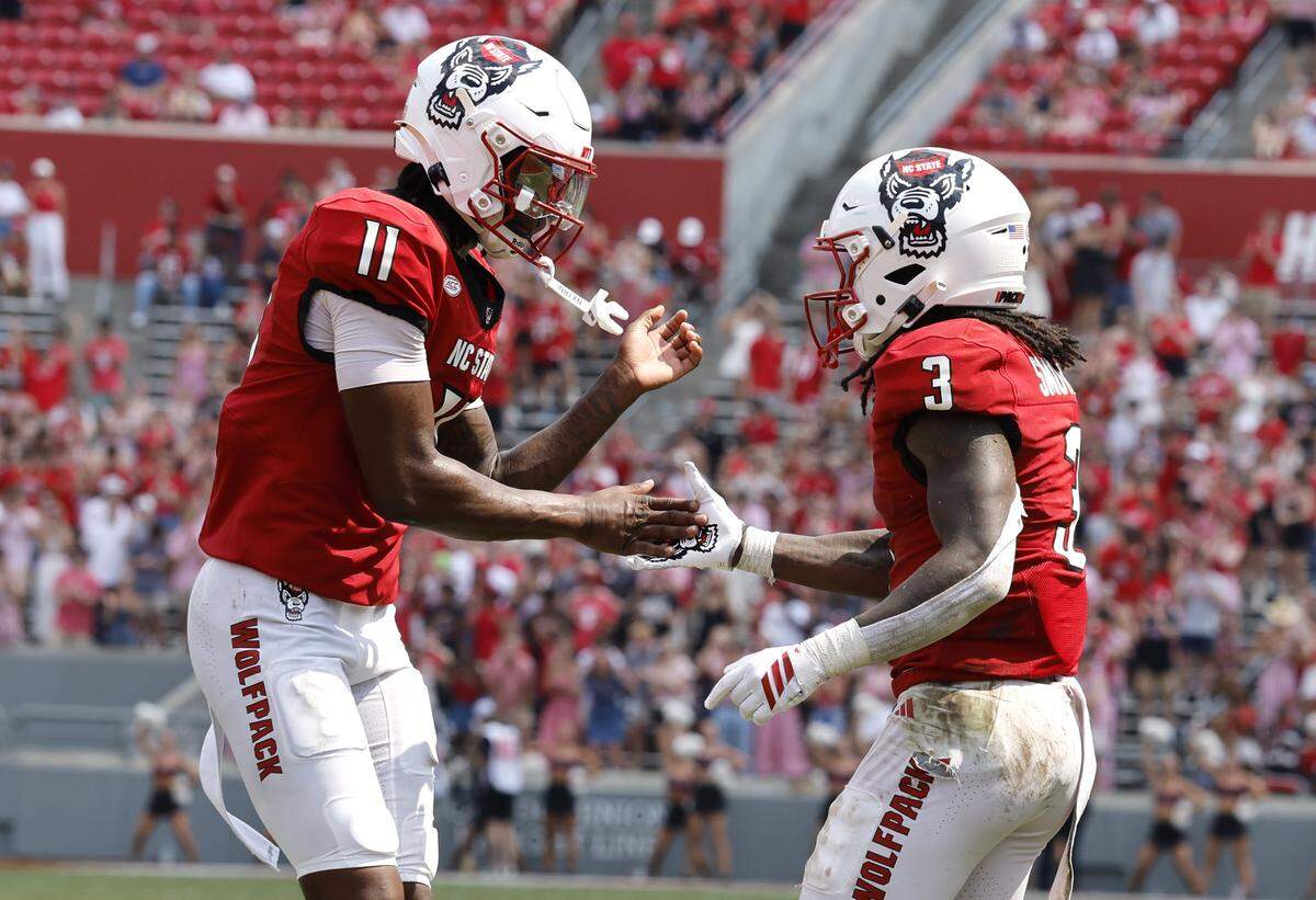 N.C. State quarterback CJ Bailey (11) celebrates with Hollywood Smothers (3) after Smothers scored on a nine-yard touchdown run during N.C. State’s 35-31 victory over Virginia at Carter-Finley Stadium in Raleigh, N.C., Sat. Sept. 6, 2025.