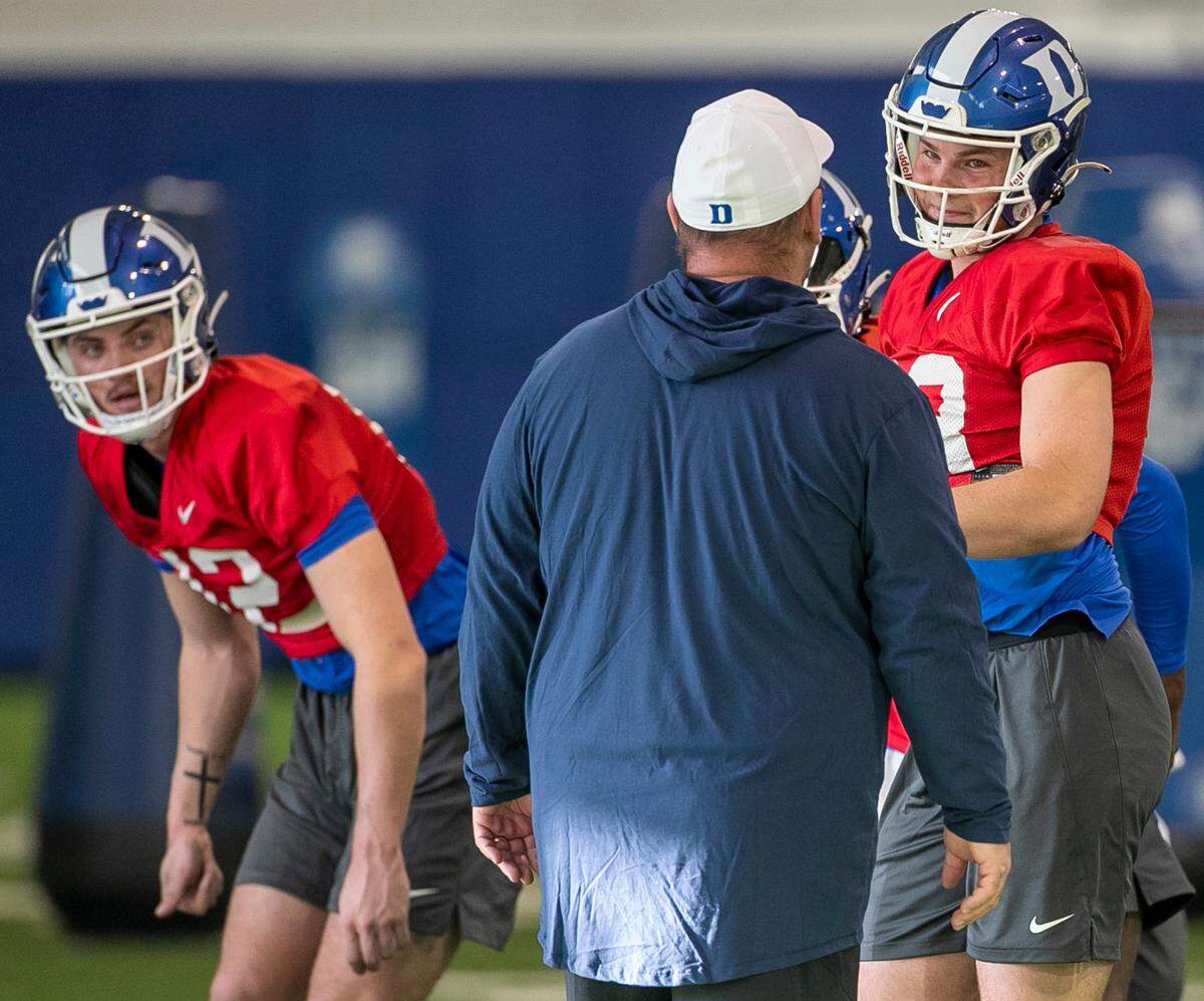 Duke quarterbacks Grayson Loftis (12), left, and Riley Leonard (13) listen to head coach Mike Elko during the Blue Devils’ spring practice on Friday, March 24, 2023 in Durham, N.C.