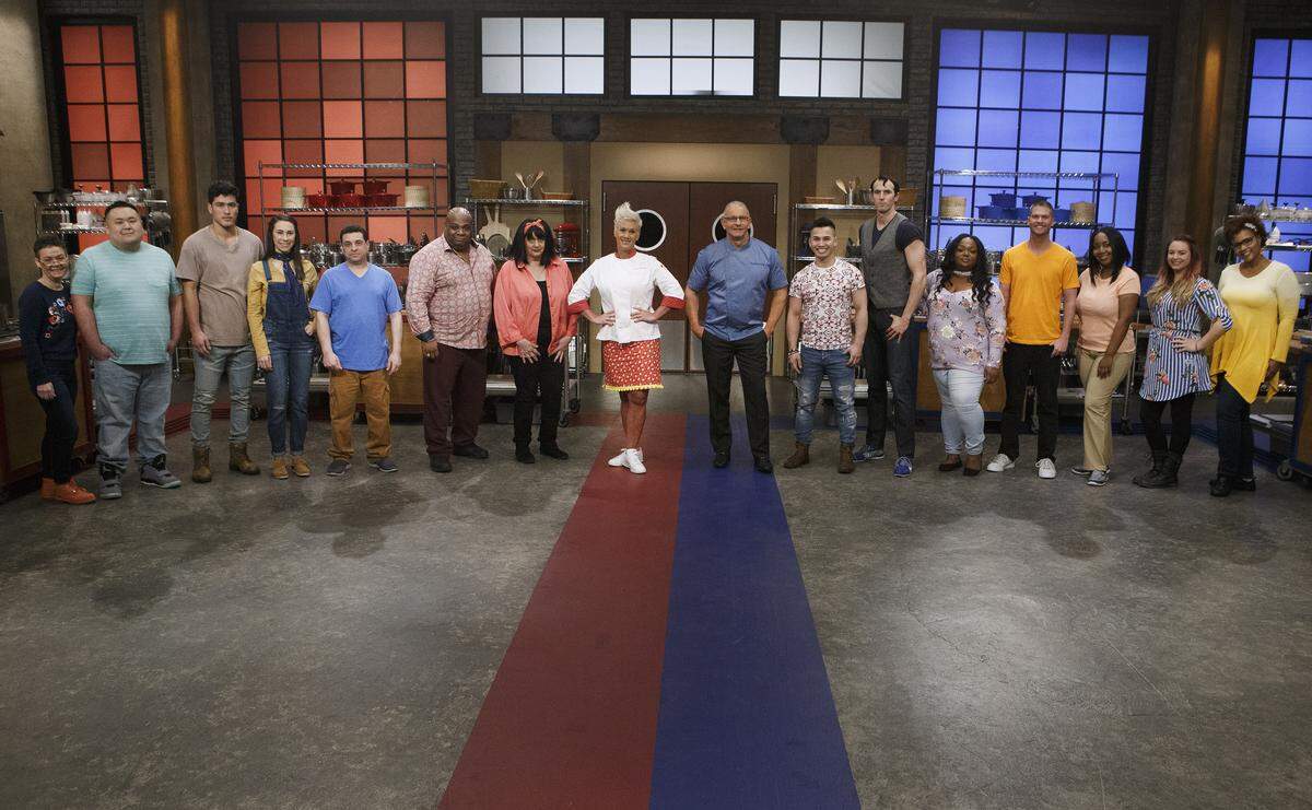 Mentors Robert Irvine and Anne Burrell pose with recruits Linda Martin, Rudy Rehberg, Bradley Garcia, Sarah Harris, Frank Scuderi, Marcus Ellis, Maryann Rapisarda, Timmy Thok, Robbie Deraffele, Janese Henry, Copan Combs, Kimberly Worthy, Jessica Paulson and Carla Waddell, as seen on Season 14 of Food Network’s “Worst Cooks in America.”