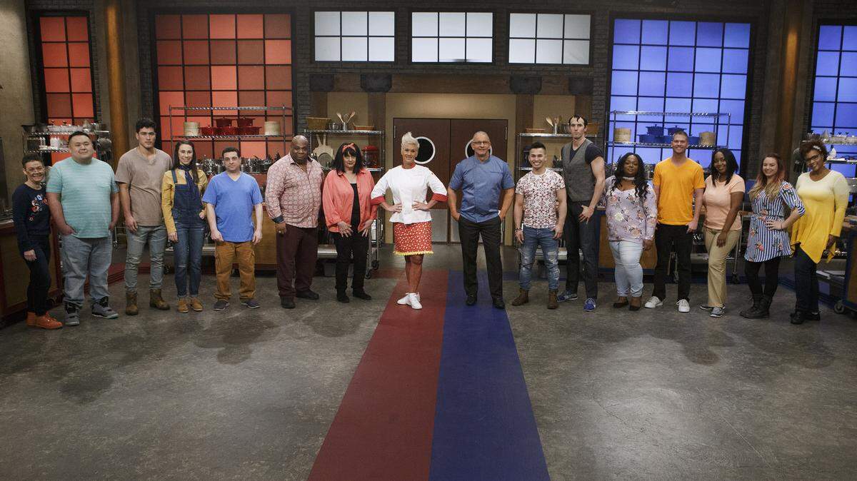 Mentors Robert Irvine and Anne Burrell pose with recruits Linda Martin, Rudy Rehberg, Bradley Garcia, Sarah Harris, Frank Scuderi, Marcus Ellis, Maryann Rapisarda, Timmy Thok, Robbie Deraffele, Janese Henry, Copan Combs, Kimberly Worthy, Jessica Paulson and Carla Waddell, as seen on Season 14 of Food Network’s “Worst Cooks in America.”