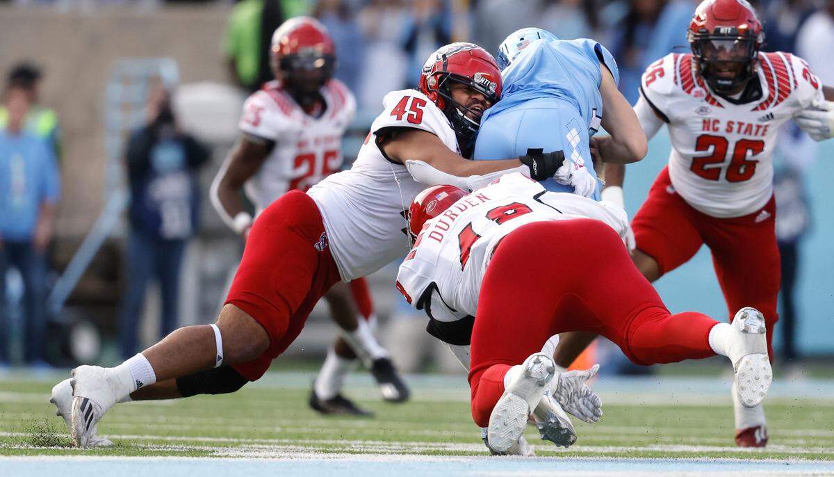N.C. State defensive tackle Davin Vann (45) and defensive tackle Cory Durden (48) tackle North Carolina quarterback Drake Maye during the first half of N.C. State’s game against UNC at Kenan Stadium in Chapel Hill, N.C., Friday, Nov. 25, 2022.
