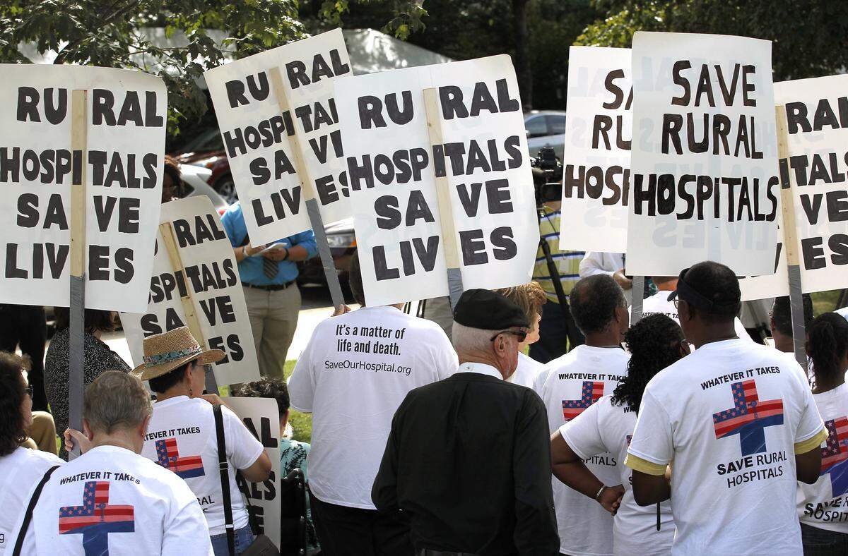 Protesters hold signs at a rally held by Belhaven Mayor Adam O'Neal after he completed his walk  all the way from Belhaven to the N.C. legislature in Raleigh to protest the closing of a local hospital in his town.