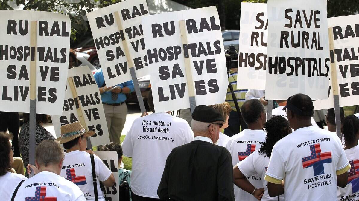 Protesters hold signs at a rally held by Belhaven Mayor Adam O'Neal after he completed his walk  all the way from Belhaven to the N.C. legislature in Raleigh to protest the closing of a local hospital in his town.