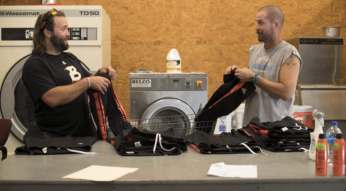 Wallace-Rose Hill assistant coach Jordan Boser, left and head coach Kevin Motsinger sort and fold uniforms prior to the Bulldogs’ game against Spring Creek on Friday, October 5, 2018 in Teachey, N.C.