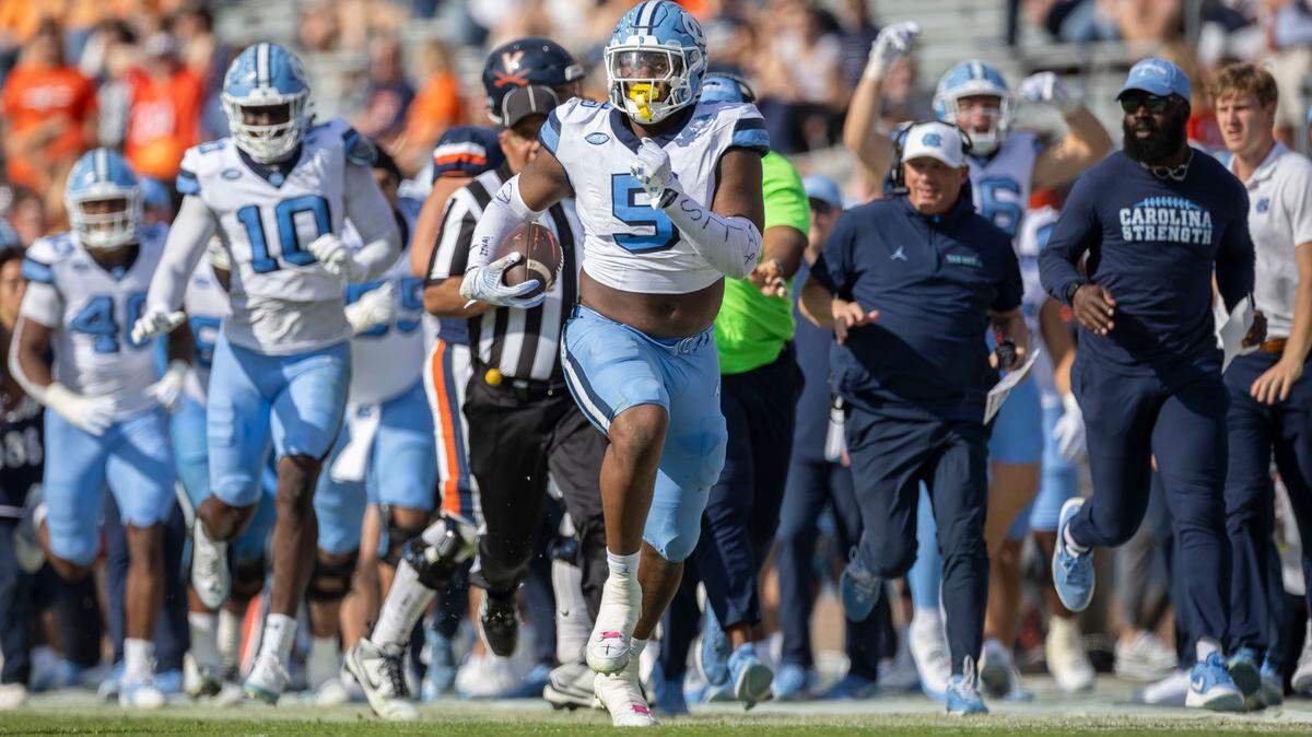 North Carolina defensive lineman Jahvaree Ritzie (5) sprints by the Tar Heels’ bench with defensive coordinator Geoff Collins looking on, as he returns an interception 84-yards for a touchdown in the third quarter to give the Tar Heels’ a 38-6 lead on Saturday, October 26, 2024 at Scott Stadium in Charlottesville, Va.