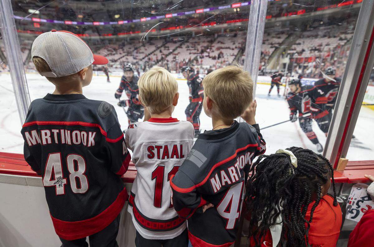 Chase Martinook, Henry Staal and Weldon Jones, watch the Carolina Hurricanes during pre-game skate, before the game against Philadelphia on Monday May 4, 2026, at Lenovo Center  in Raleigh, N.C.  Martinook and Staal are sons of Carolina players Jordan Martinook and Jordan Staal. 