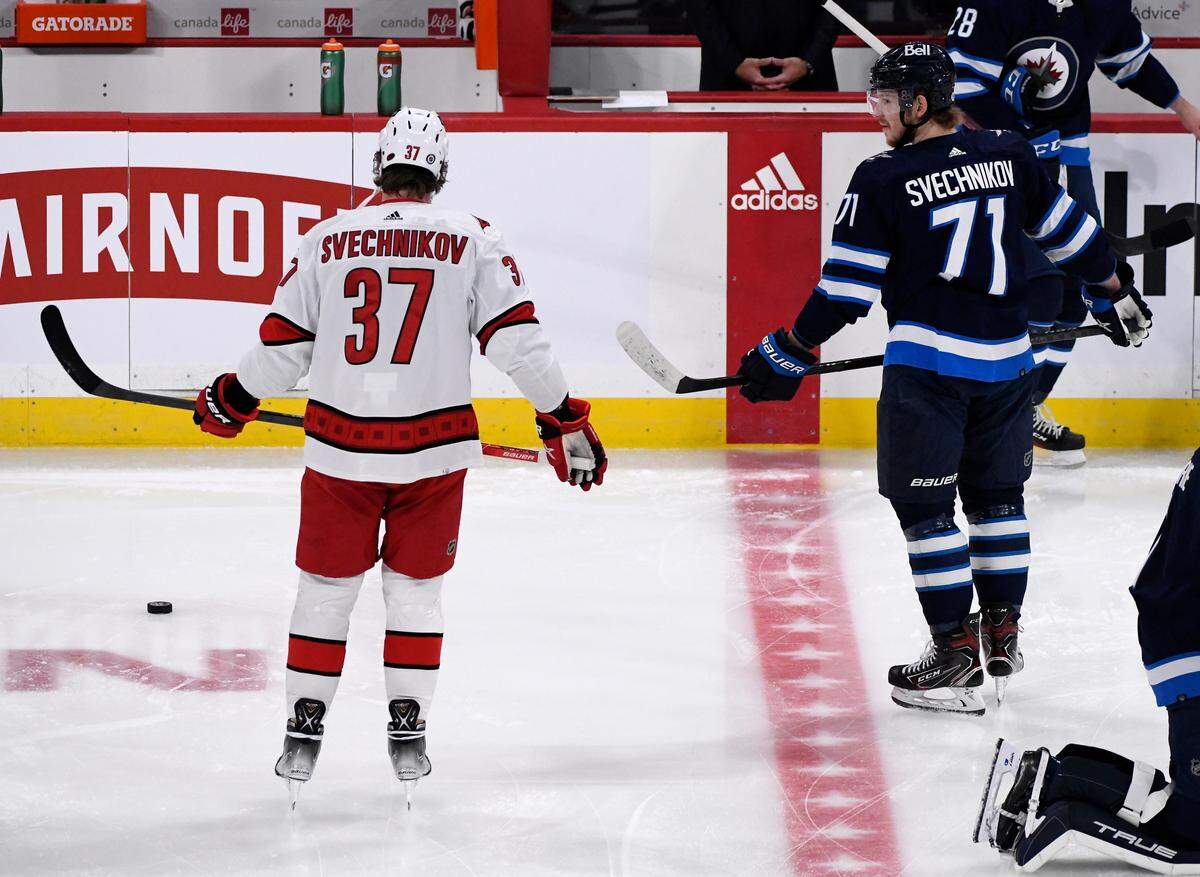 Winnipeg Jets’ Evgeny Svechnikov (71) talks to his brother Andrei Svechnikov (37) of the Carolina Hurricanes during the warm-up skate before an NHL game in Winnipeg, Manitoba, Tuesday, Dec. 7, 2021. (Fred Greenslade/The Canadian Press via AP)