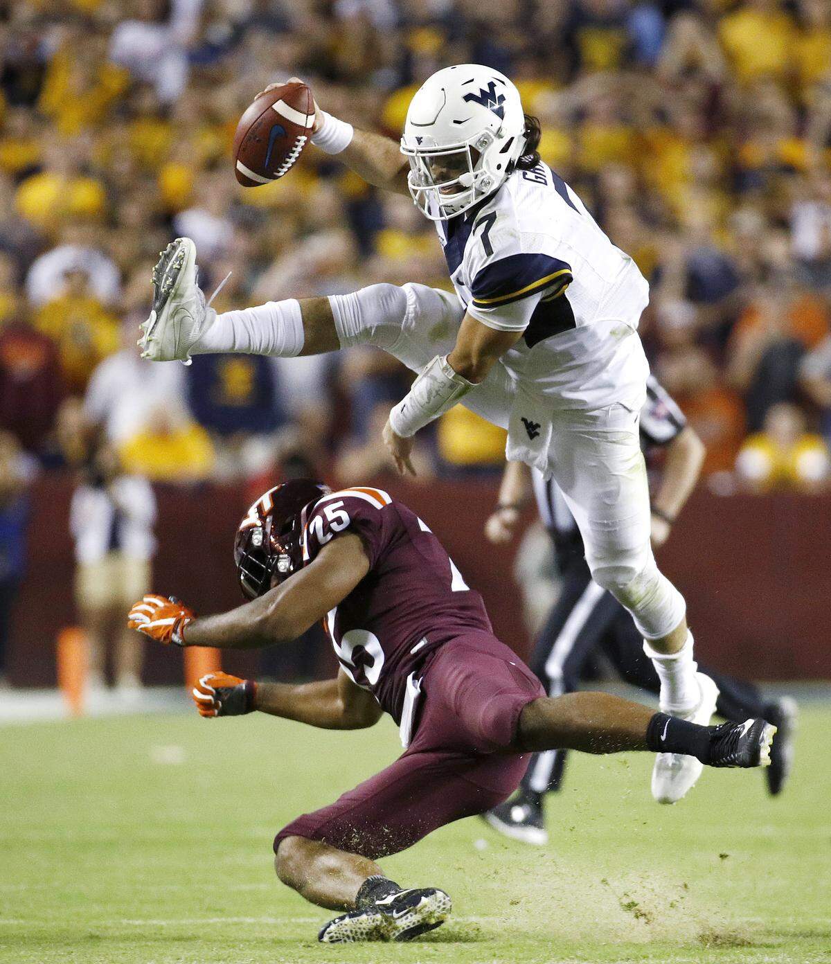 West Virginia quarterback Will Grier, top, leaps over Virginia Tech linebacker Anthony Shegog as he rushes for a first down in the second half of an NCAA college football game in Landover, Md., Sunday, Sept. 3, 2017.