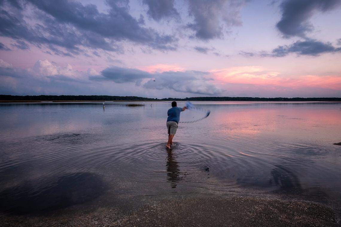 A fisherman casts his net from a shell island in Murrells Inlet, S.C. as the rising tide covers most of the shoreline. Oct. 16, 2020.