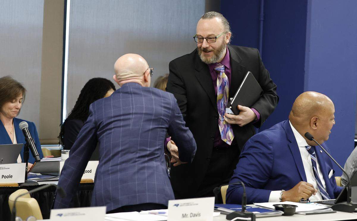 Wade Maki, a professor at UNC Greensboro and chair of the system’s Faculty Assembly, greets board member Gene Davis after Professor Maki spoke during a meeting of UNC Board of Governors in Raleigh, N.C., Thursday, Feb. 26, 2026.