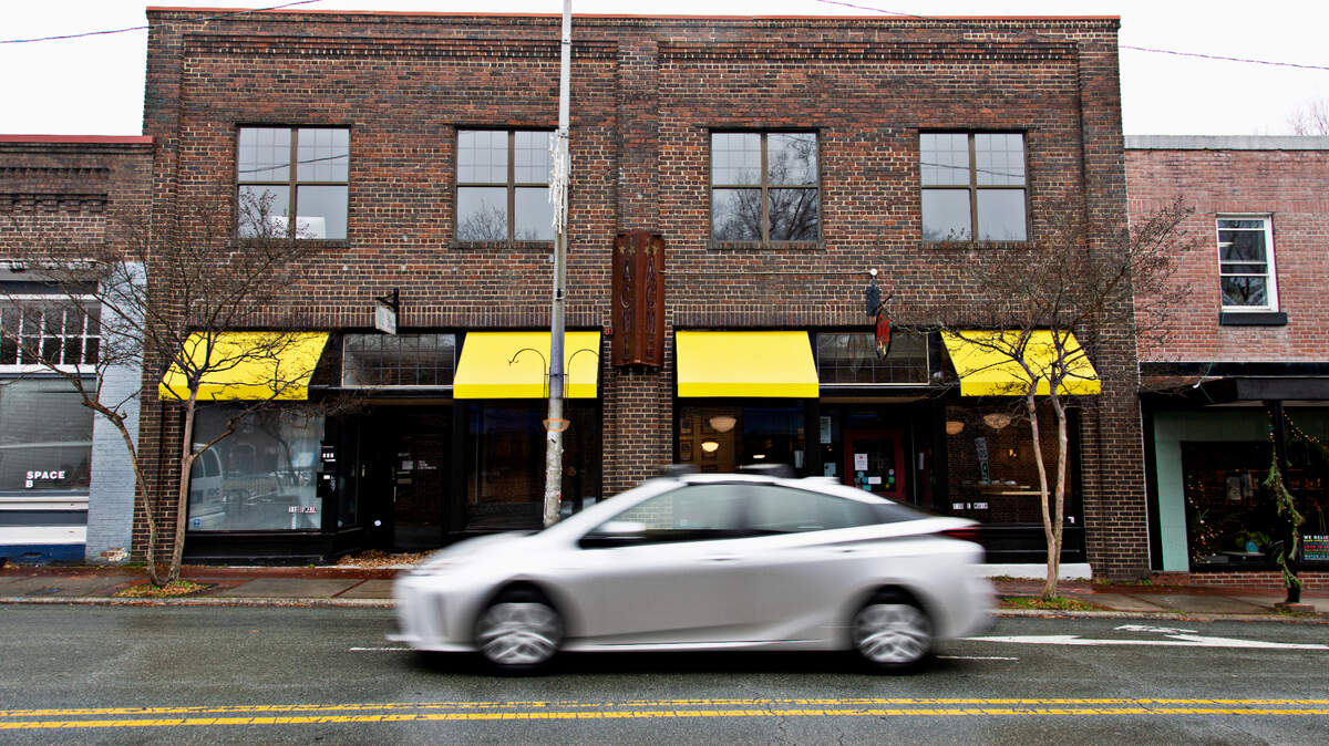 A car drives past Acme Food & Beverage Co. on Main Street in downtown Carrboro.