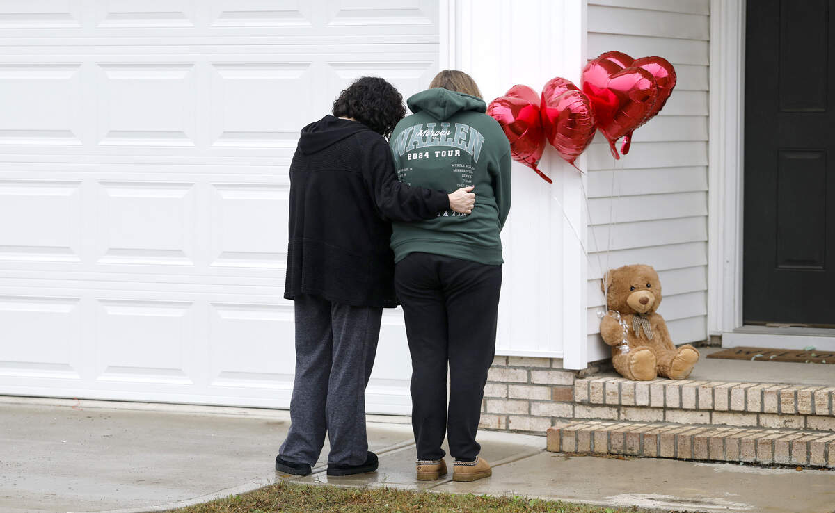 Rachel Ross and her mother Debra Riley bow their heads after placing a teddy bear and four balloons on the porch of the home of Wellington Dickens III in Zebulon, N.C., Wednesday, Oct. 29, 2025. Dickens faces four charges of murder in the deaths of his children 6-year-old Leah Dickens, 9-year-old Zoe Dickens, 10-year-old Wellington Dickens IV and 18-year-old Sean Brasfield, his stepson.
