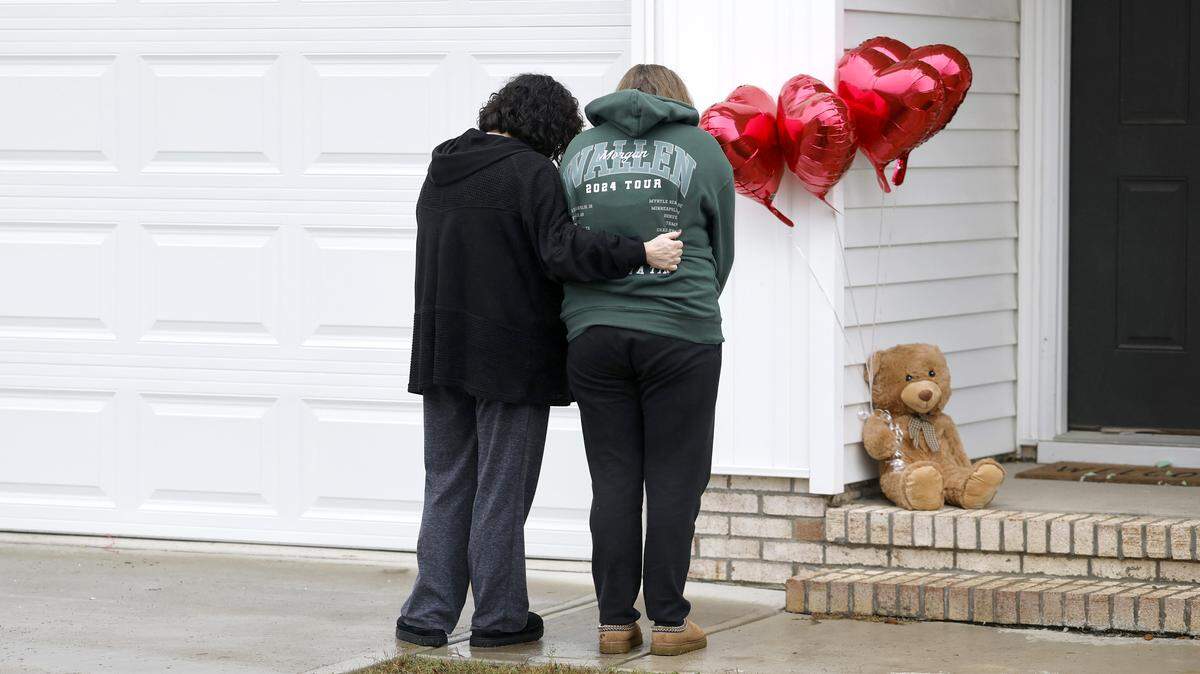 Rachel Ross and her mother Debra Riley bow their heads after placing a teddy bear and four balloons on the porch of the home of Wellington Dickens III in Zebulon, N.C., Wednesday, Oct. 29, 2025. Dickens faces four charges of murder in the deaths of his children 6-year-old Leah Dickens, 9-year-old Zoe Dickens, 10-year-old Wellington Dickens IV and 18-year-old Sean Brasfield, his stepson.
