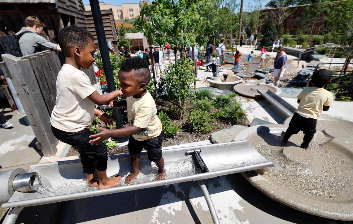 Samuel Rose, 4, left, and his twin brothers Asa, center, and Austin, 2, play in one of the water features at Gipson Play Plaza at Dix Park during a preview day Saturday, May 24, 2025. T