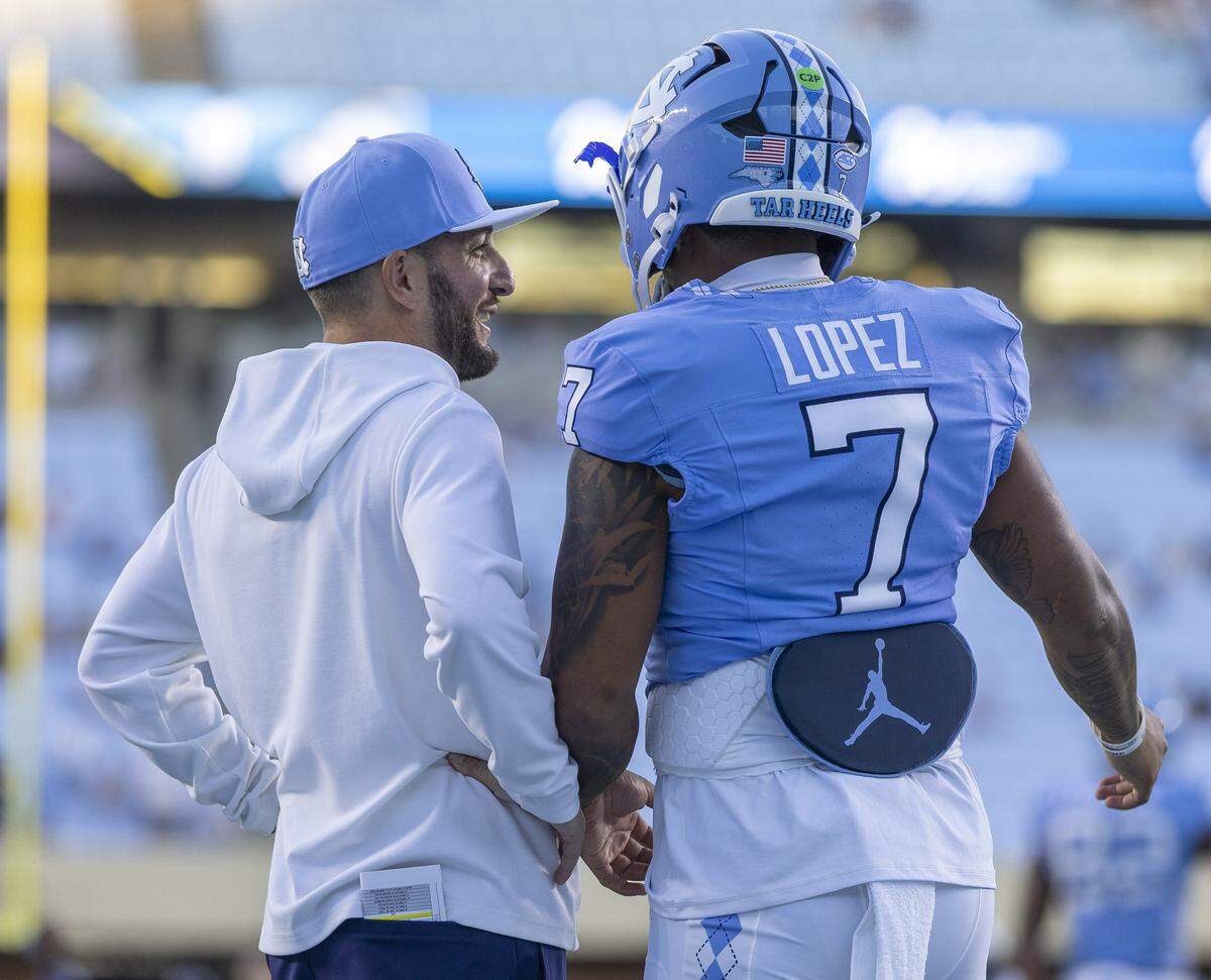 North Carolina quarterbacks coach Matt Lombardi talks with starting quarterback Gio Lopez (7) prior to the Tar Heels’ season opening game against Texas Christian University on Monday, September 1, 2025 in Chapel Hill, N.C.  