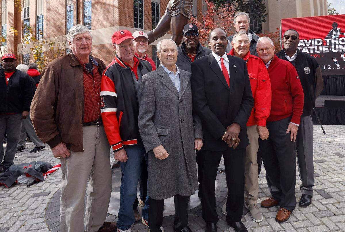Members of the 1974 National Championship team, from left, Craig Kuszmaul, Biff Nicholls, team trainer Don Reibel, Eddie Biedenbach, Phil Spence, David Thompson, Mark Moeller, Tommy Burleson, Howard Pickett and Jerry Hunt pose after Thompson’s statue was unveiled outside Reynolds Coliseum in Raleigh, N.C., Wednesday, Dec. 6, 2023.
