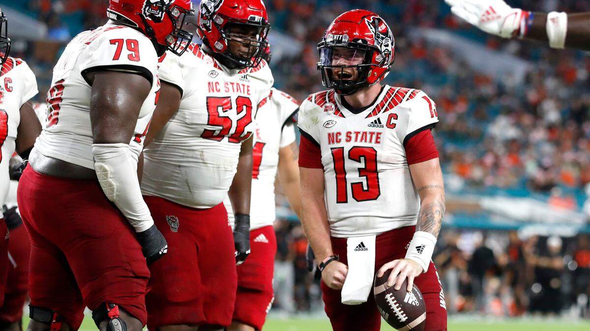 N.C. State quarterback Devin Leary (13) celebrates with Ikem Ekwonu (79) and Timothy McKay (52) after scoring on a 17-yard touchdown run during the second half of Miami’s 31-30 victory over N.C. State at Hard Rock Stadium in Miami Gardens, Fla. Saturday, Oct. 23, 2021.