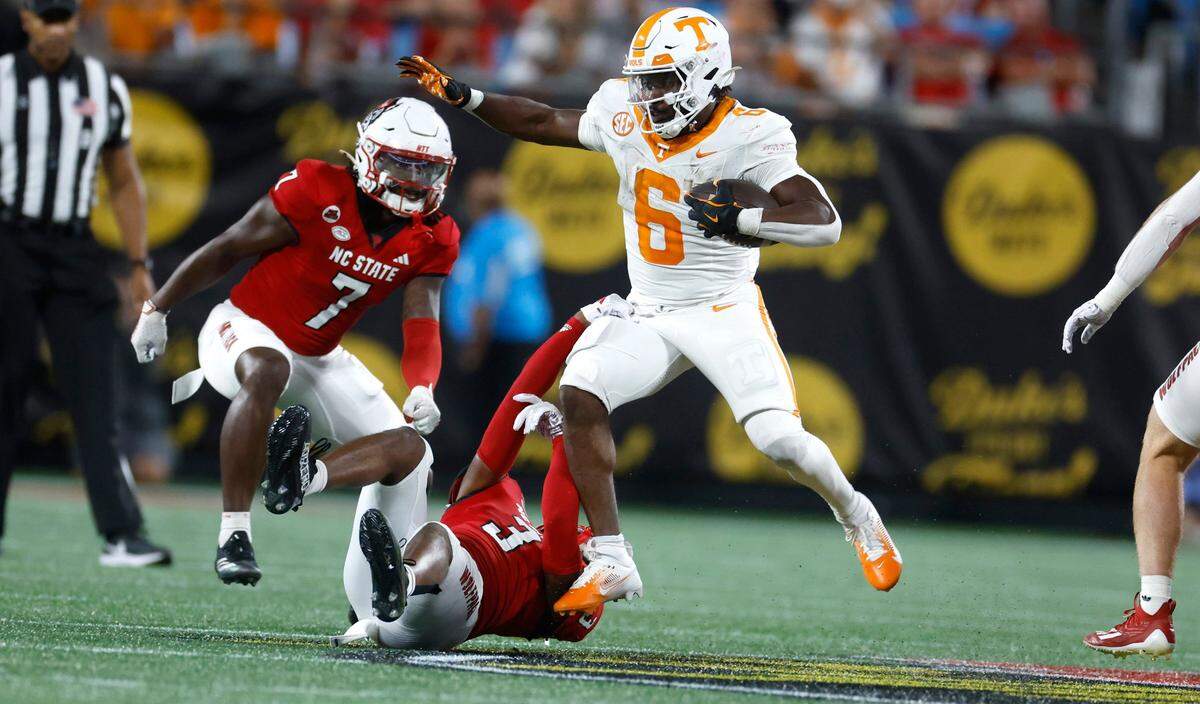 Tennessee running back Dylan Sampson (6) tries to avoid N.C. State cornerback Aydan White (3) during the first half of N.C. State’s game against Tennessee in the Duke’s Mayo Classic at Bank of America Stadium in Charlotte, N.C., Saturday, Sept. 7, 2024.