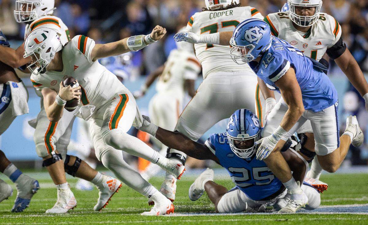 North Carolina’s Kaimon Rucker (25) slows Miami quarterback Tyler Van Dyke (9) as he is dropped for an 11-yard loss in the third quarter on Saturday, October 14, 2023 at Kenan Stadium in Chapel Hill, N.C.