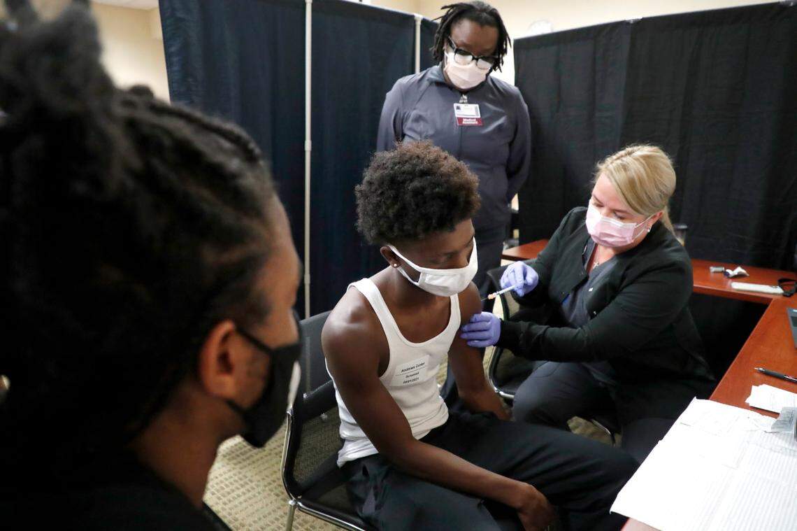 As his brother Ka’trell Green, 18, left, watches Maleke Green,16, gets his first COVID-19 vaccine shot from Melissa Weider, RN, during the WakeMed Back-to-School Blitz vaccine clinic at the WakeMed Raleigh Campus in Raleigh, N.C., Sunday, August 1, 2021. Medical assistant Lakiza James watches.