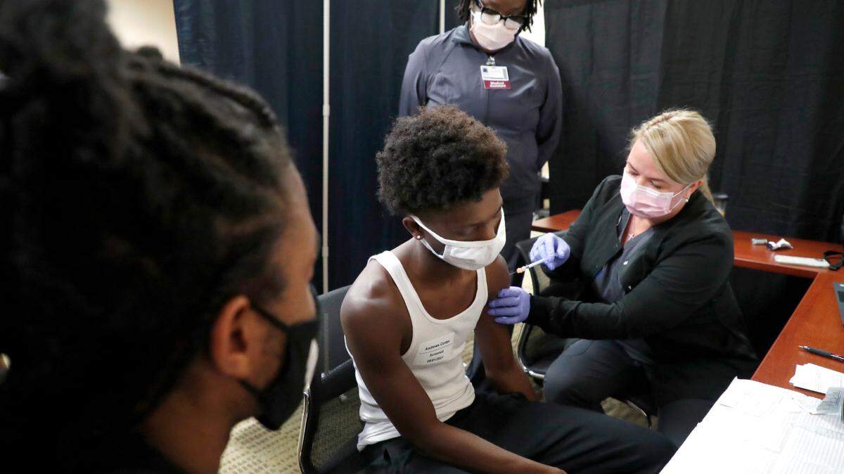 As his brother Ka’trell Green, 18, left, watches Maleke Green,16, gets his first COVID-19 vaccine shot from Melissa Weider, RN, during the WakeMed Back-to-School Blitz vaccine clinic at the WakeMed Raleigh Campus in Raleigh, N.C., Sunday, August 1, 2021. Medical assistant Lakiza James watches.