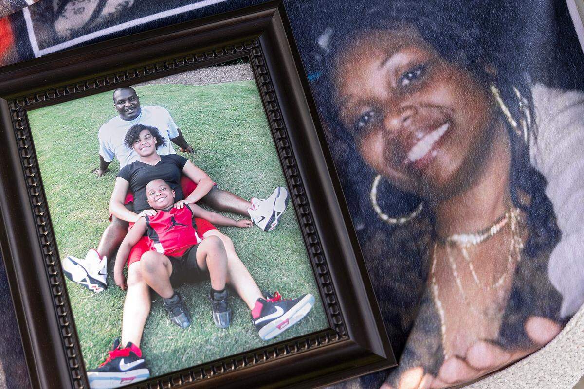 A framed photograph of Atari Thomas, his daughter, Hannah Esquilin, and son, Braylon, as seen on Wednesday, May 3, 2023, sits atop a blanket featuring a photograph of his wife, Tiffany. Thomas had the blanket made for Tiffany to mark their seven-year anniversary in 2020. Tiffany was eight months pregnant when she developed COVID-19 and, after having an emergency C-section, died in 2021.