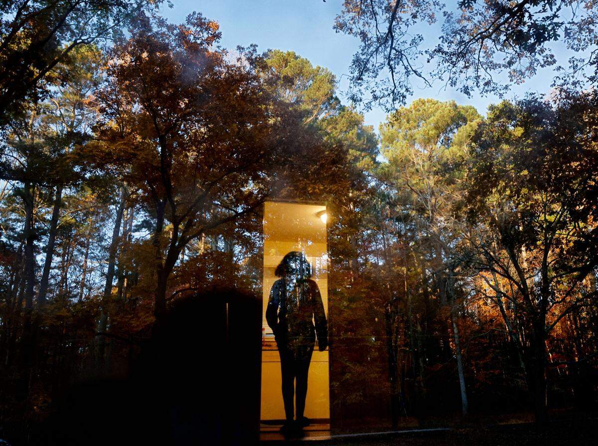 Sheba Everett walks inside as autumn foliage reflects in the front door of her Durham, N.C. home on Thursday, Nov. 3, 2022. Everett, who for two years has rented the house where she lives with her five daughters, received an eviction letter after the Eno River Association planned to transfer the land to the state park system.