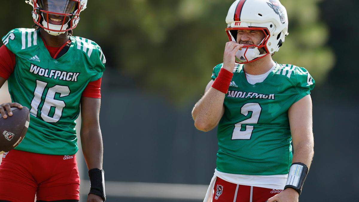 N.C. State quarterback CJ Bailey (16) laughs with quarterback Grayson McCall (2) during the Wolfpack’s first practice in Raleigh, N.C., Wednesday, July 31, 2024.
