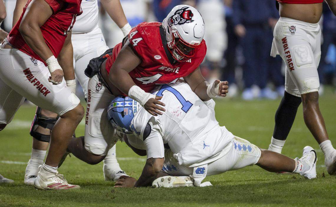 N.C. State defensive tackle Brandon Cleveland (44) falls on North Carolina quarterback Gio Lopez (7), injuring him, after Lopez was sacked by Travail Price (13) in the third quarter on Saturday, November 29, 2025 at Carter-Finley Stadium in Raleigh, N.C.&nbsp;