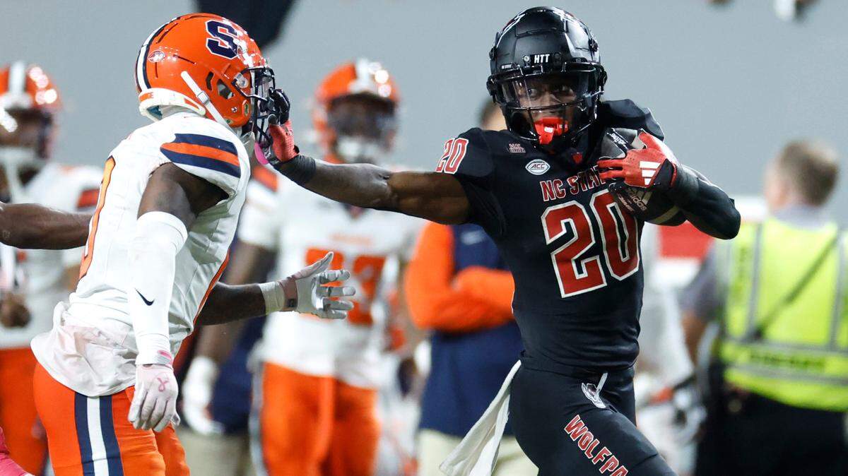 N.C. State running back Hollywood Smothers (20) stiff-arms Syracuse defensive back Duce Chestnut (0) on a 72-yard reception during the second half of Syracuse’s 24-17 victory over N.C. State at Carter-Finley Stadium in Raleigh, N.C., Saturday, Oct. 12, 2024.