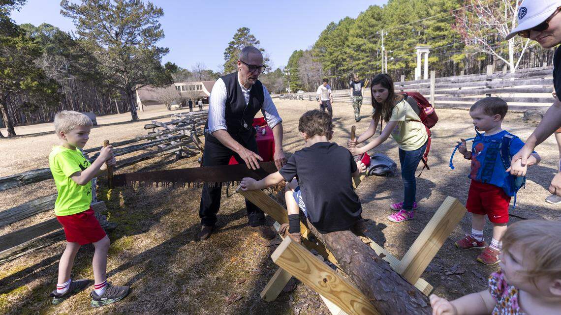 Robert Bemis, a heritage trades interpreter specialist, leads a two-person crosscut saw demonstration for homeschoolers and parents during a homeschool day event at Bennett Place State Historic Site in Durham on Friday.