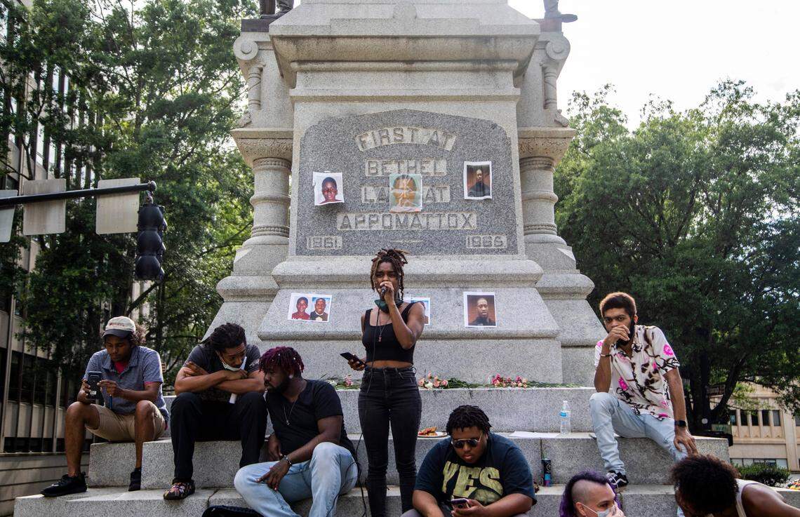 Yasmine McLeod, center, reads a poem from the base of the Confederate monument at the NC State Capitol before a crowd of about 200 demonstrators protesting police violence, systemic racism and Confederate monuments Friday, June 12, 2020.