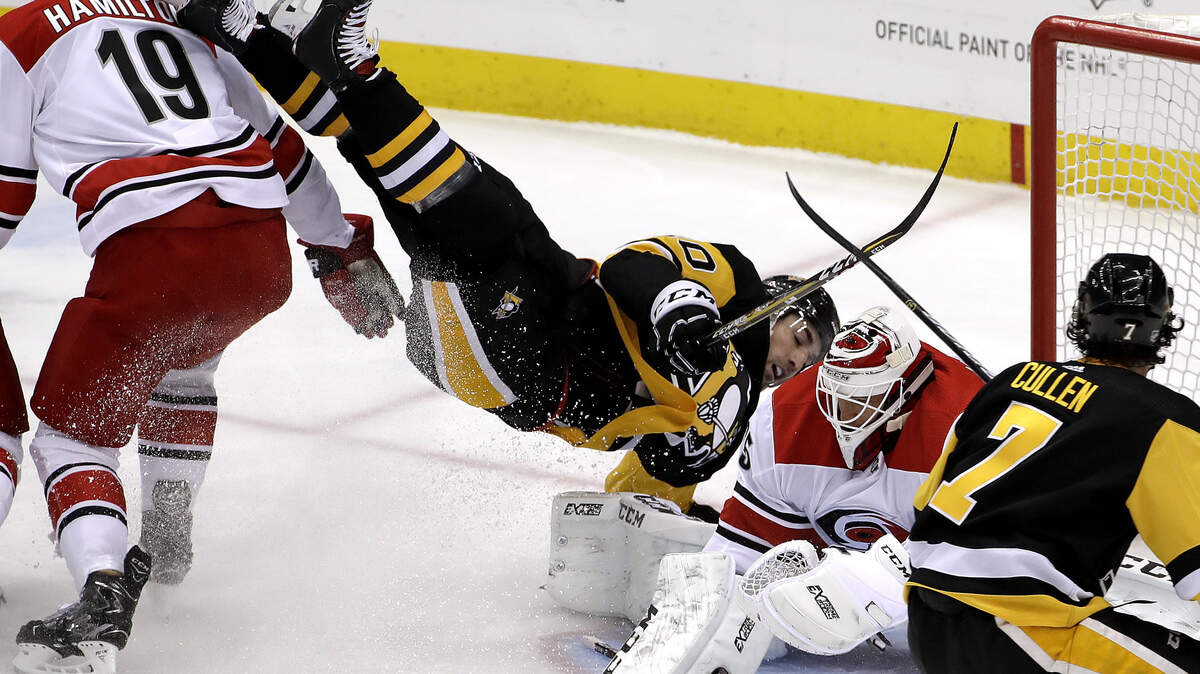 Pittsburgh Penguins’ Garrett Wilson, center, is upended next to Carolina Hurricanes goaltender Curtis McElhinney, second from right, during the first period of an NHL hockey game in Pittsburgh, Tuesday, Feb. 5, 2019. (AP Photo/Gene J. Puskar)