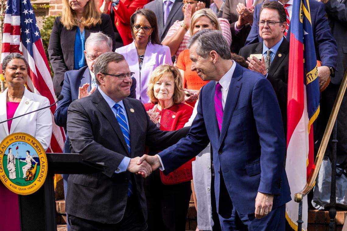Gov. Roy Cooper, left, shakes hands with House Speaker Tim Moore before signing a Medicaid expansion bill into law during a ceremony at the Executive Mansion Monday, March 27, 2023.
