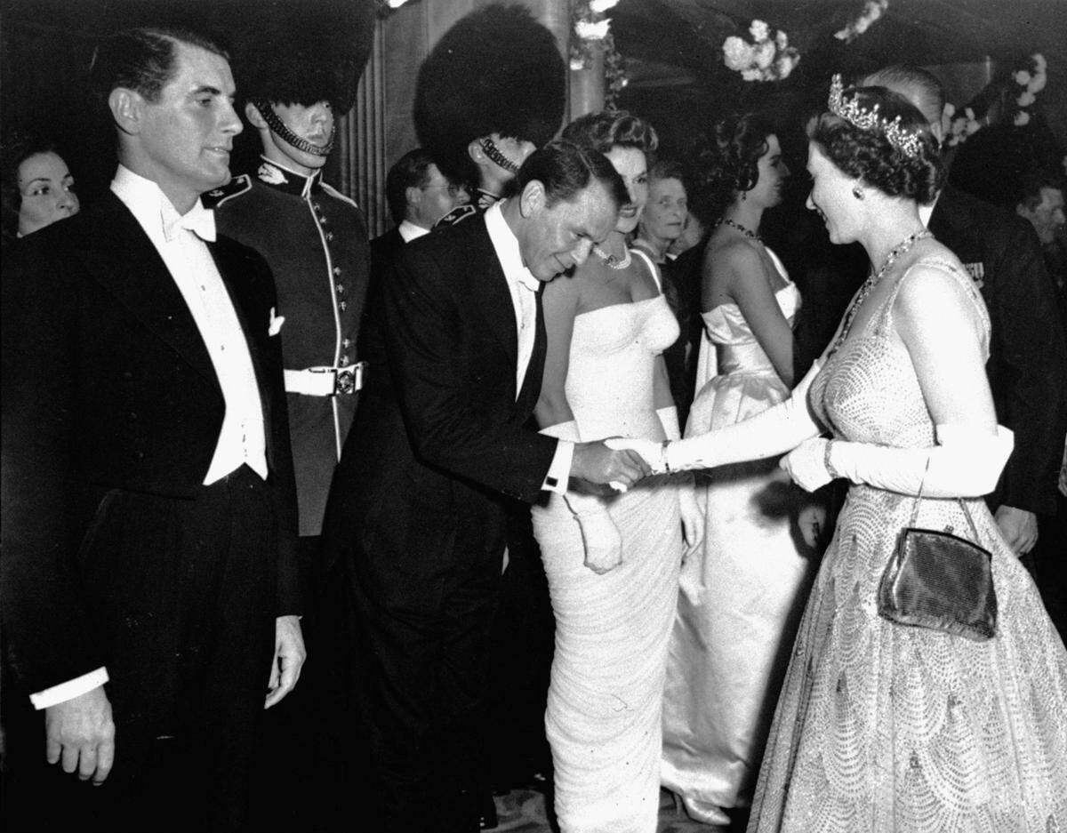American singer and actor Frank Sinatra is presented to Queen Elizabeth II in the foyer of the Odeon Theatre, Leicester Square, London, October 27, 1958, at the premiere of Danny Kaye’s film, “Me And The Colonel”. Beyond him (partially obscured) is French actress Nicole Maurey.